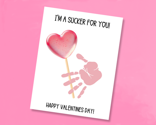 Handprint art featuring a pink heart lollipop with a blank space where the handprint is pressed as if holding the lollipop. Includes Happy Valentine's Day message at the bottom.